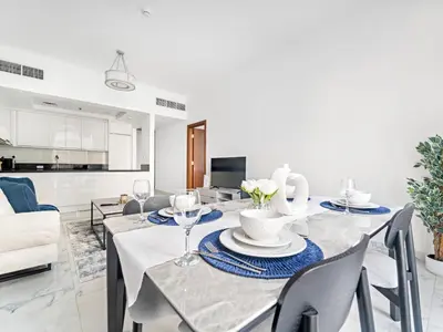a dining room and living room with a table and chairs at Charming City View w 1BDR Apartment In Noura Tower in Dubai