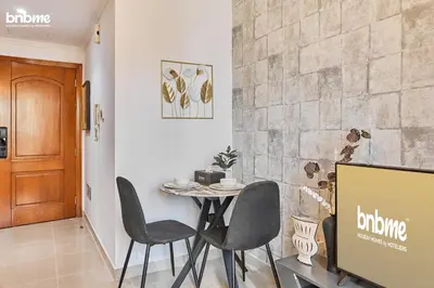 a dining room with a table and chairs and a wall at bnbmehomes - Manchester Tower in Dubai