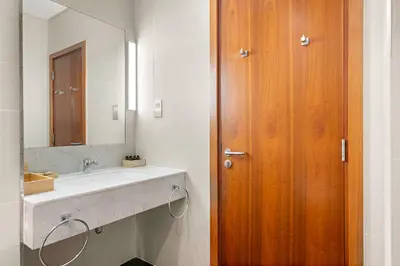 a bathroom with a sink and a wooden door at Silkhaus Entrepreneur Work & Stay Studio in DIFC in Dubai