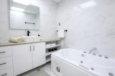 a white bathroom with a tub and a sink at Teremok Holiday Homes in Dubai