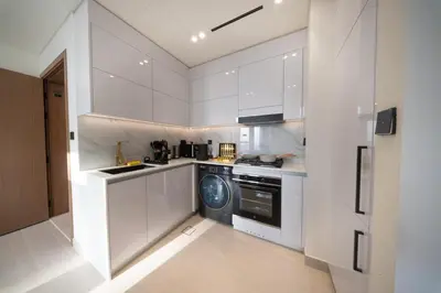 a kitchen with white cabinets and a washing machine at Sleeps 4 I Circle Mall I Epic Pool in Dubai
