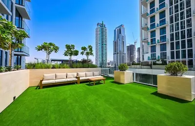 an apartment patio with green grass and a couch at Sleeps 4 I Circle Mall I Epic Pool in Dubai