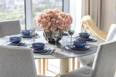 a table with a vase of flowers and wine glasses at Canal Front Luxe, Elegant 2BR with Water Views in Dubai