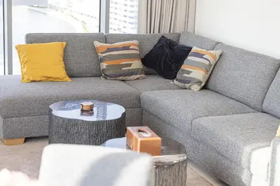 a living room with a gray couch with pillows at Canal Front Luxe, Elegant 2BR with Water Views in Dubai