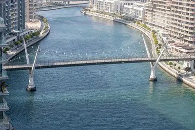 a bridge over a river in a city with buildings at Canal Front Luxe, Elegant 2BR with Water Views in Dubai