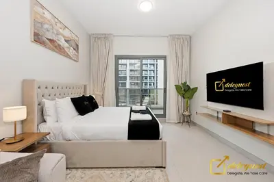 a white bedroom with a bed and a tv at Elite Studio in Dubai Hills Near Dubai Hills Mall in Dubai