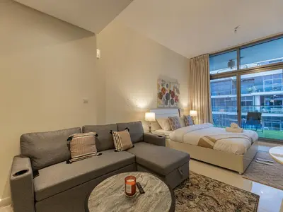 a living room with a couch and a bed at Spacious Golf & Pool View Home with Huge Balcony in Dubai
