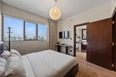 a bedroom with a large bed and a large window at Nonna house Stylish 1BR and Panoramic Studio, City, Golf, Lake view in Dubai