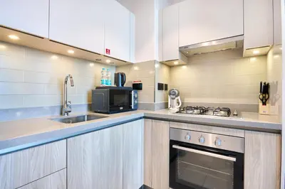 a large kitchen with a sink and a microwave at STAY BY LATINEM Luxury 1BR plus study Holiday Home W2405 in Dubai