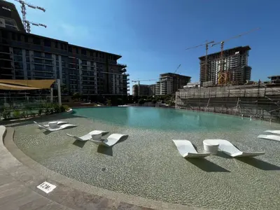 a swimming pool with white chairs in a city at Daniels 1BR at Viridian by Central Park, City Walk in Dubai