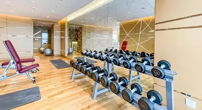 a gym with rows of dumbbells and a red chair at Studio in Dubai