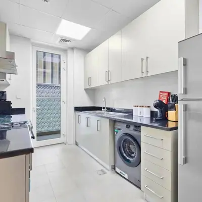 a white kitchen with a washing machine in it at Dunya Tower in Dubai