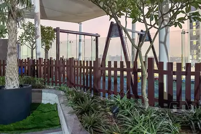 a wooden fence with a swing in a garden at Cozy 2BR in Paramount Dubai with Burj Khalifa View in Dubai