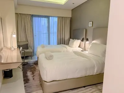 a hotel room with two beds and a window at Cozy 2BR in Paramount Dubai with Burj Khalifa View in Dubai