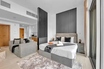 a bedroom with a large bed and a chair at The Fitness Suite JVC - Pool View - Zaya Hameni in Dubai