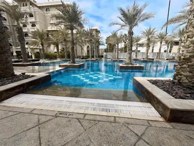 a swimming pool with palm trees and a building at Beachfront Escape Sea-View Balcony Palm Jumeirah in Dubai