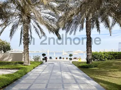 a walkway with palm trees in front of the water at Beachfront Escape Sea-View Balcony Palm Jumeirah in Dubai