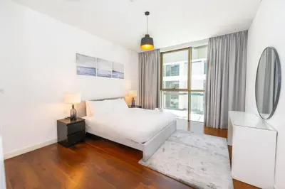 a white bedroom with a bed and a mirror at Stylish 1BR Stay in City Walk Building 10 in Dubai