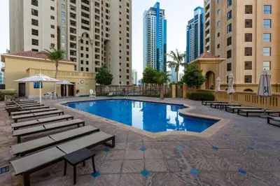a large swimming pool with benches and buildings at Vacationer l Cozy 2 Bed l Breathtaking Sea and Ain Dubai Views in Dubai