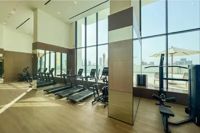 a gym with treadmills and ellipticals and windows at Vacationer l Elegant 1 Bedroom l Near to Park and Mall l JVC in Dubai
