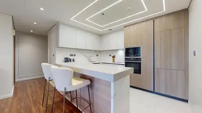 a kitchen with white cabinets and a counter with stools at Vacationer l Mesmerizing 2 Bed l Sea and Ain Dubai View l JBR in Dubai