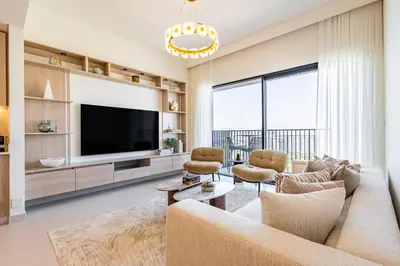 a living room with a couch and a tv at Superhost - 1BR Apartment, Balcony, Pool & Gym , Dubai Hills in Dubai
