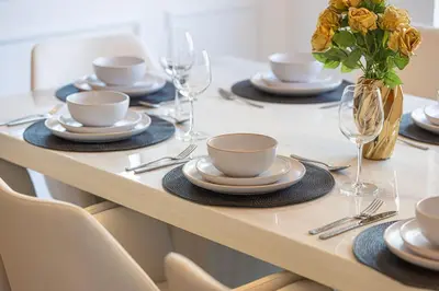 a table with plates and glasses and a vase of flowers at Large 4 Bed Apt with Burj View and 8 Min Walk to Mall by Vista Stays DXB in Dubai