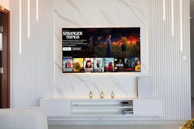 a living room with a tv on a wall at Large 4 Bed Apt with Burj View and 8 Min Walk to Mall by Vista Stays DXB in Dubai