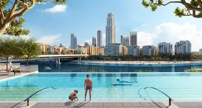 two people standing in a swimming pool with a city at Luxury & Modern Unit in Emaar Beachfront in Dubai
