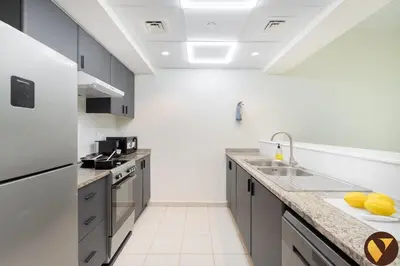 a kitchen with a sink and a refrigerator at Vogue The Greens Al Alka near Mall of the Emirates, One Bedroom Apartment with Balcony and Vibrant community View, Access to all Amenities in Dubai