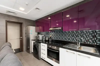 a kitchen with purple cabinets and a sink at Cayan Tower, Dubai Marina - Onelink in Dubai