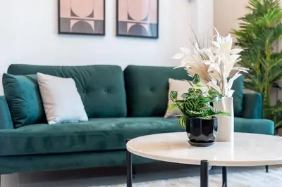 a living room with a green couch and a table at Silkhaus in Al Tajer in Souk al Bahar Direct Access in Dubai