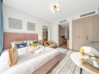 a bedroom with a large bed and a living room at Peninsula One Suites by Prestige Nest in Dubai