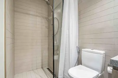 a bathroom with a toilet and a glass shower at Frank Porter - Peninsula One in Dubai