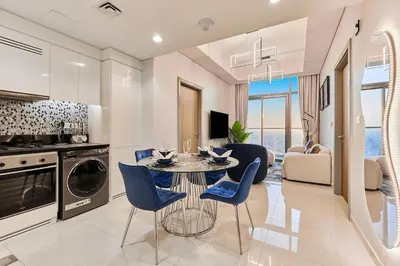 a kitchen and living room with a table and chairs at The Iconic Stay 2BR in Dubai