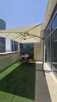 a patio with a table and a white umbrella at Partition with attached washroom in Dubai