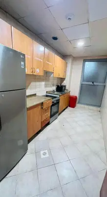 a kitchen with wooden cabinets and a stainless steel refrigerator at Platinum Budget Stay Dubai In Tecom Near Metro in Dubai