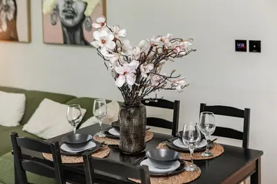a dining room table with a vase with flowers in it at Elegant 2BR Apartment in Binghatti Heights in Dubai