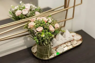 a vase filled with pink roses in front of a mirror at Elegant 2BR Apartment in Binghatti Heights in Dubai