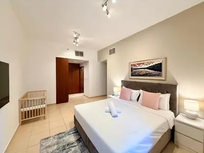 a bedroom with a large white bed with pink pillows at Brand-New 4BR on JBR Beach Near metro, mall By Sunkissed Holiday Homes in Dubai