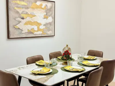 a dining room table with chairs and a painting at Brand-New 4BR on JBR Beach Near metro, mall By Sunkissed Holiday Homes in Dubai