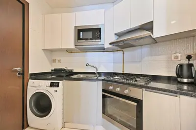 a kitchen with a washing machine and a microwave at Bloomfields STU in Business Bay, Bayz by Danube in Dubai