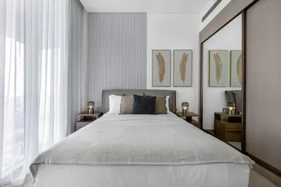 a bedroom with a large white bed with two lamps at Chic 1BR Retreat with Private Pool and Balcony in JVC in Dubai