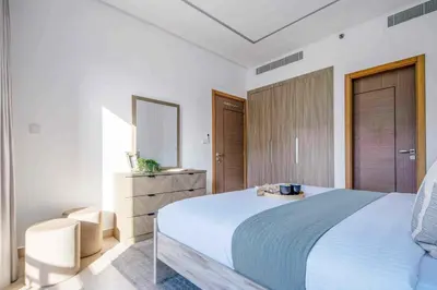 a white bedroom with a large bed and a dresser at Frank Porter - Sunrise Legend in Dubai