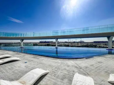 a swimming pool with two white chairs in front of a building at Frank Porter - Skyz By Danube in Dubai