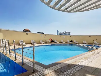a swimming pool on top of a building with chairs at Frank Porter - Goldcrest Executive in Dubai