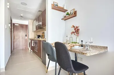 a kitchen with a table with chairs and a counter at Frank Porter - Goldcrest Executive in Dubai