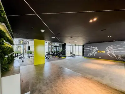 a lobby with a gym with chairs and a yellow wall at High floor studio with stunning views in Aykon City in Dubai