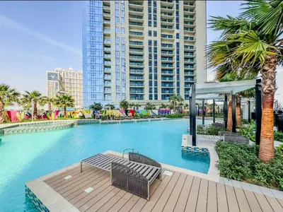 a swimming pool with two benches and a building at High floor studio with stunning views in Aykon City in Dubai
