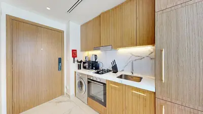 a kitchen with wooden cabinets and a sink and a stove at Modern Furnished Studio Azizi Riviera in Dubai